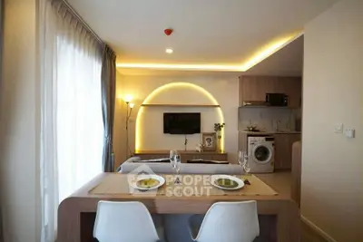 Modern open-plan living room with stylish dining area and kitchen appliances.