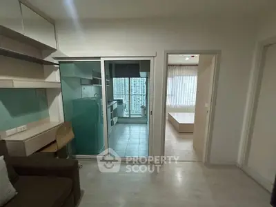 Modern apartment interior with open kitchen and bedroom view, featuring sleek design and natural light.