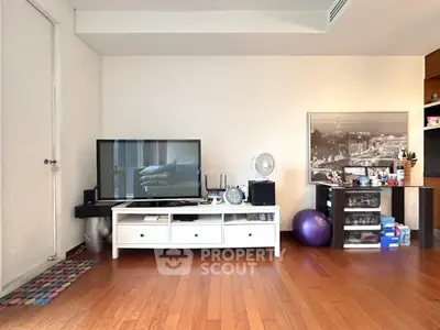 Spacious living room with modern decor and hardwood floors, featuring a TV stand and stylish artwork.