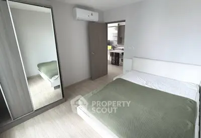 Modern bedroom with mirrored wardrobe and green bedding in a stylish apartment.