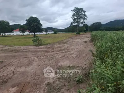 Expansive land plot with scenic views, ideal for development or agriculture, surrounded by lush greenery and distant hills.