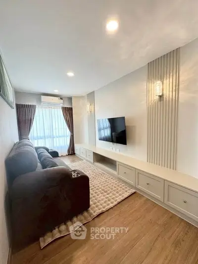 Modern living room with cozy sofa, wall-mounted TV, and elegant lighting