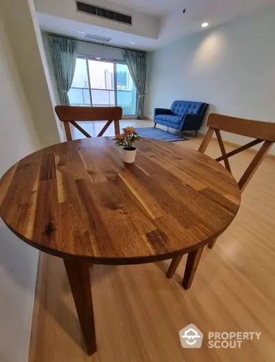 Spacious living room with wooden dining table and city view balcony.