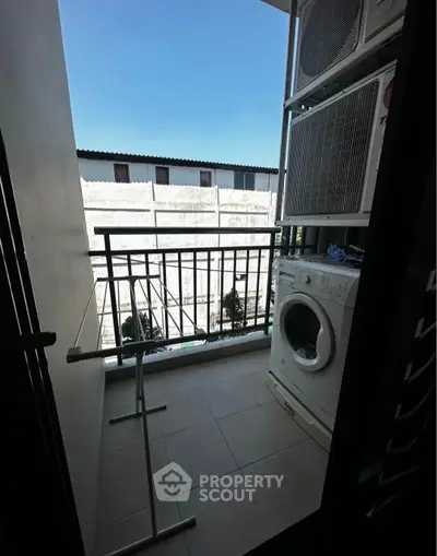 Compact balcony with washing machine and drying rack, ideal for urban living.