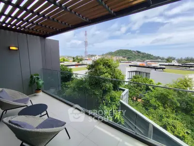 Luxurious balcony with stunning view of lush greenery and distant hills, perfect for relaxation.