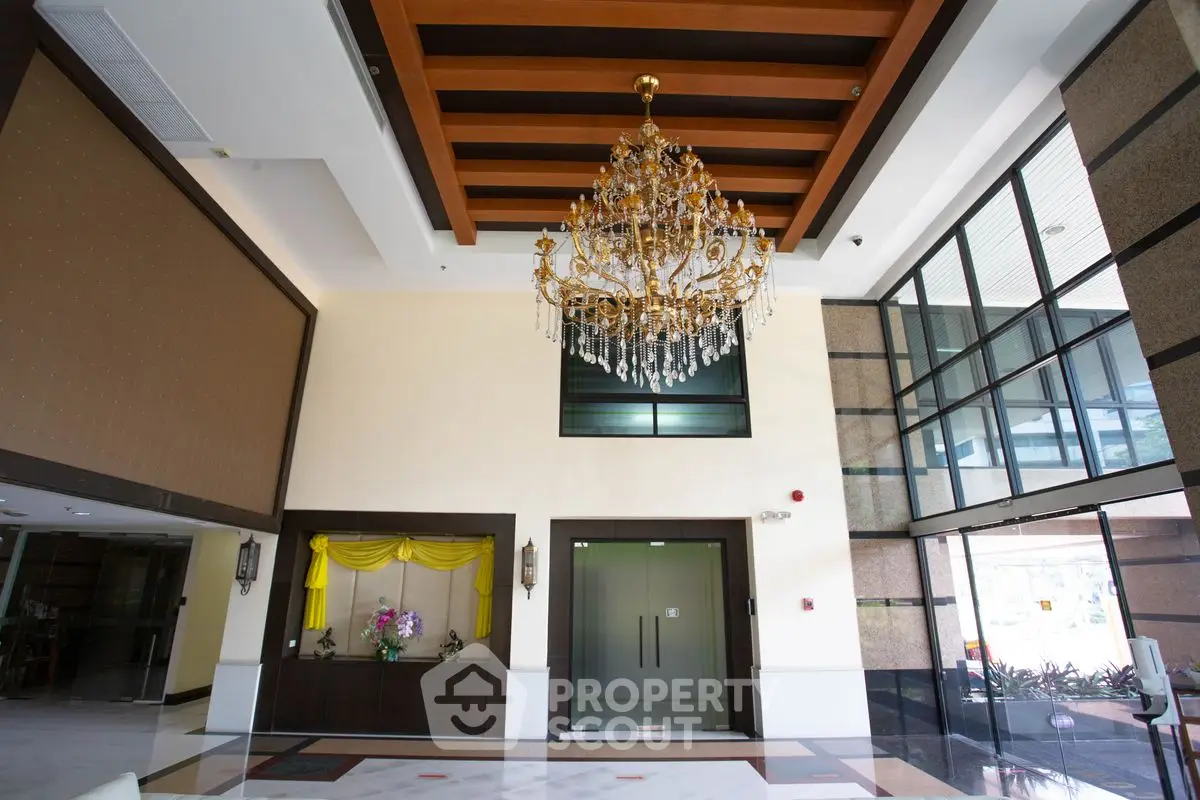 Luxurious building entrance with grand chandelier and modern design.