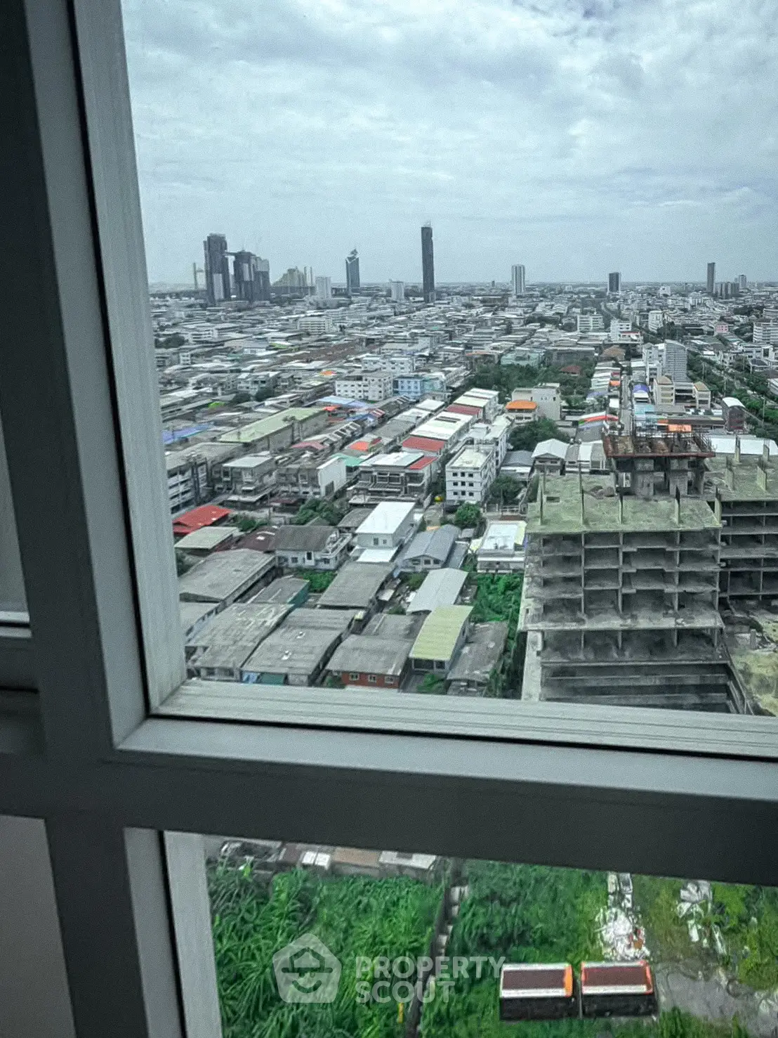 Stunning cityscape view from high-rise window showcasing urban skyline and construction site.