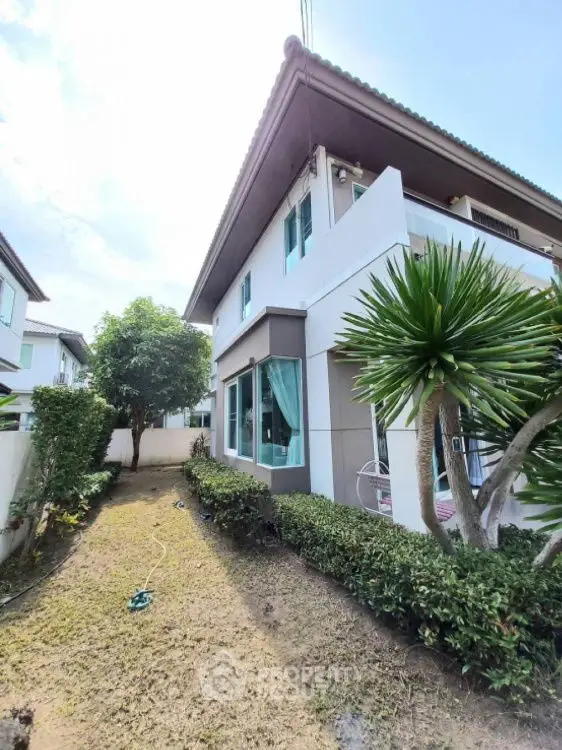Charming two-story house with lush garden and modern exterior design.
