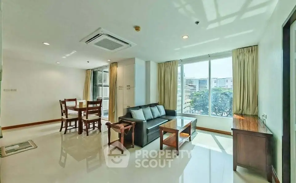 Spacious living room with large windows and modern furniture in a bright apartment.