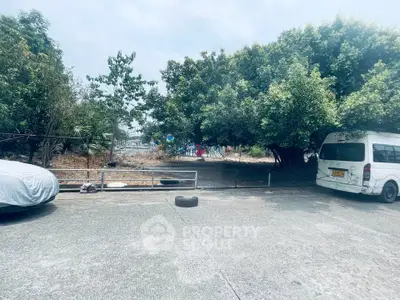 Spacious outdoor parking area with lush greenery and ample space for vehicles.