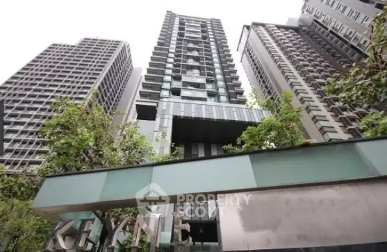 Modern high-rise building with sleek architecture and lush greenery in urban setting.