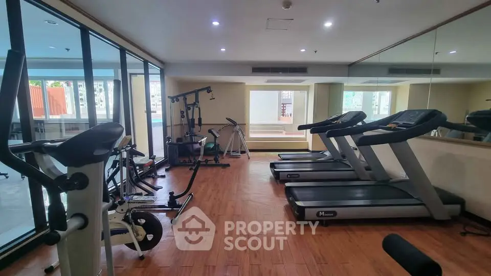 Spacious gym with modern equipment and wooden flooring in a residential building.