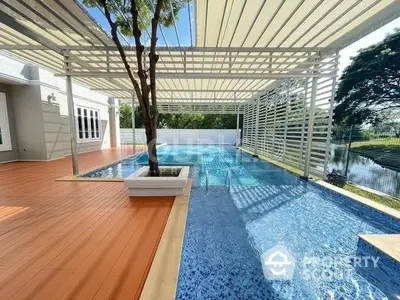 Luxurious poolside outdoor living space with modern pergola, elegant decking, and lush greenery, perfect for entertaining and relaxation.