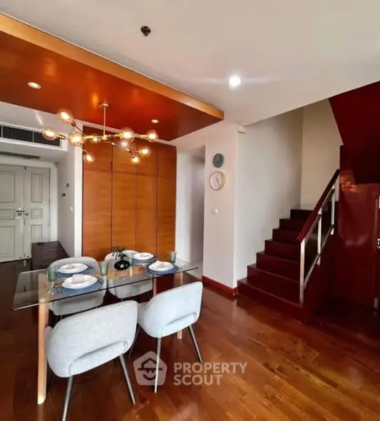 Modern dining area with stylish lighting and wooden staircase in a contemporary home.