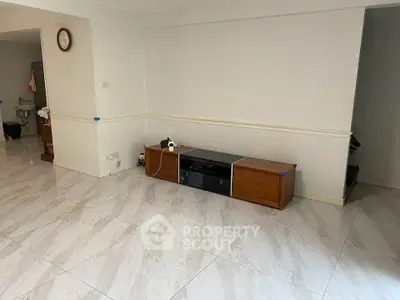 Spacious living room with modern tiled flooring and minimalist furniture.