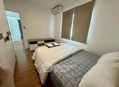 Cozy bedroom with modern decor and natural light, featuring a comfortable bed and stylish wooden flooring.