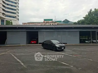 Spacious parking area with multiple garages and a modern building backdrop.