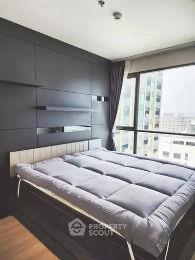 Modern bedroom with large window and city view, featuring sleek black paneling and cozy bedding.