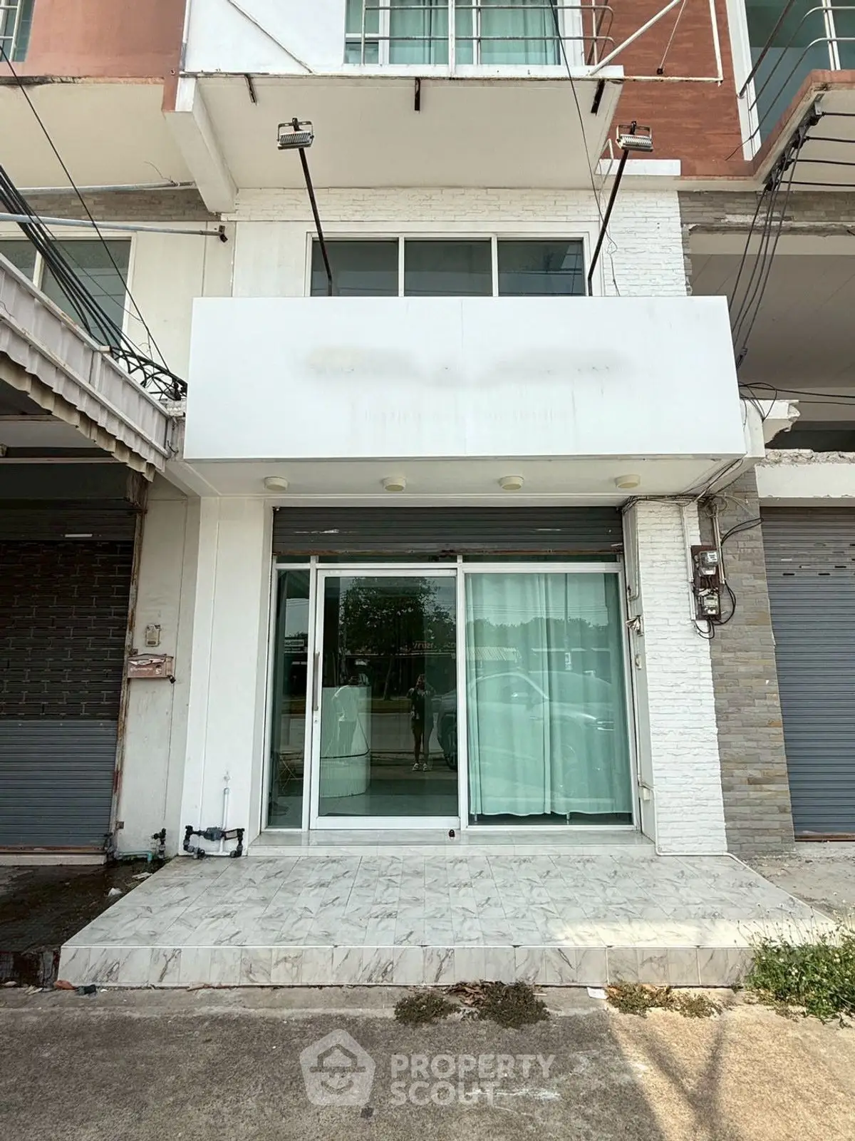 Commercial property with glass facade and roller shutter in urban setting.