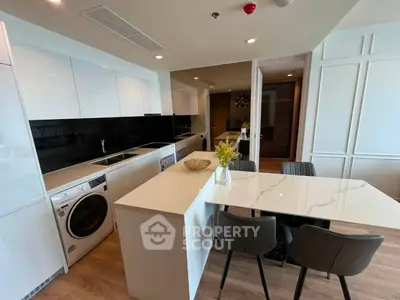 Modern kitchen with sleek white cabinets, island seating, and integrated appliances in a stylish apartment.