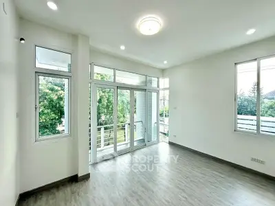 Spacious living room with large windows and balcony access, offering abundant natural light and serene views.