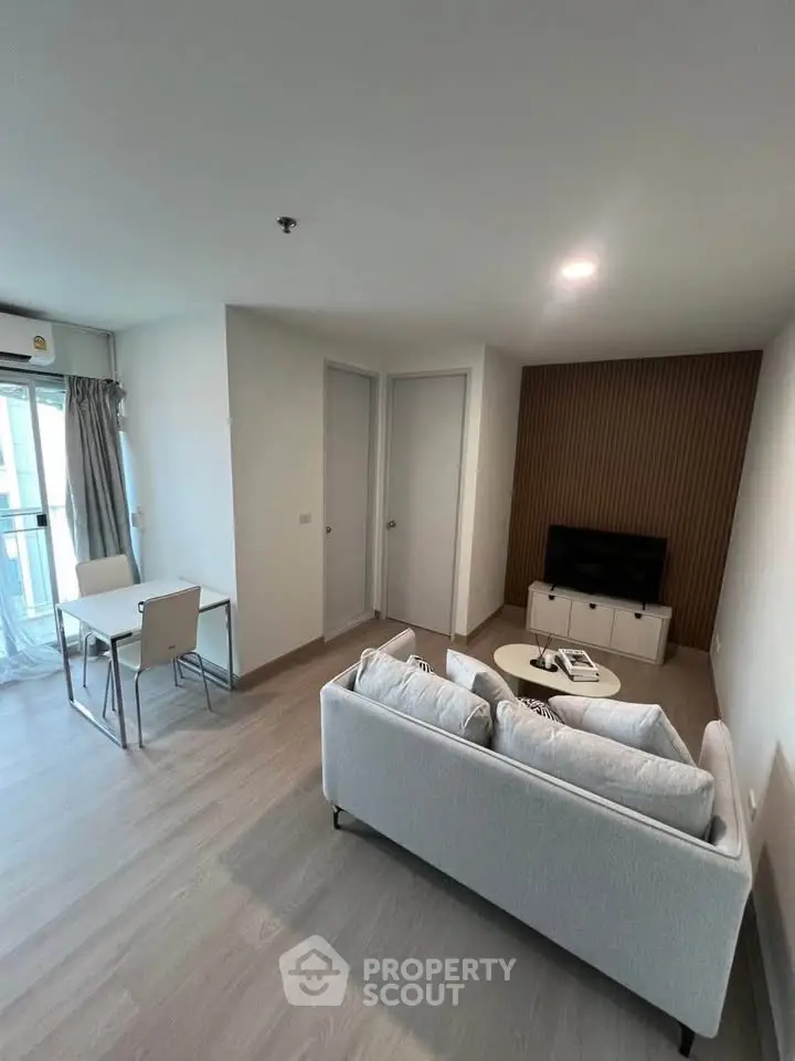 Modern living room with cozy sofa, TV, and dining area in a bright apartment.