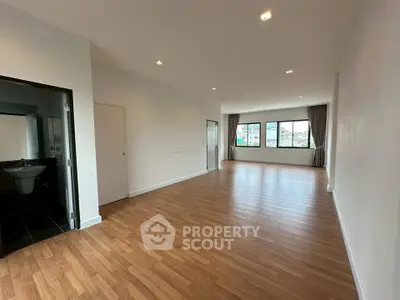 Spacious open-plan living area with large windows and wooden flooring
