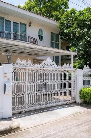 Charming white house with ornate gate and lush greenery