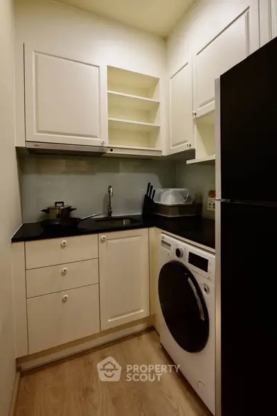 Compact kitchen with modern appliances and sleek cabinetry in cozy apartment