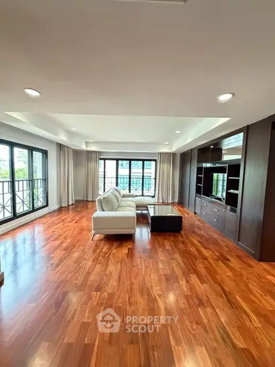 Spacious living room with hardwood floors and modern furniture in a luxury apartment.
