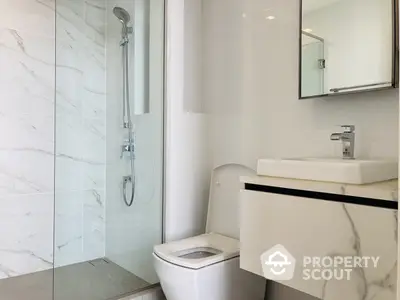 Sleek modern bathroom with marble tiles, glass shower enclosure, and stylish fixtures, perfect for a contemporary home.