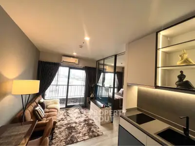 Modern open-plan living room with cozy seating and stylish kitchen area, featuring large windows and ample natural light.