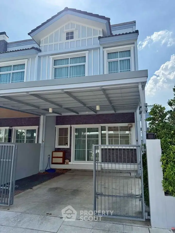 Charming two-story house with modern facade and gated driveway, perfect for family living.