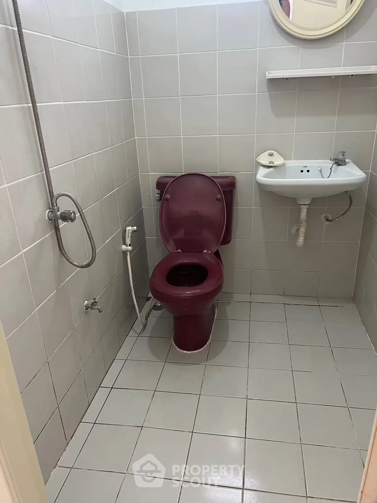 Compact bathroom with maroon fixtures and tiled walls, featuring a shower and small sink.
