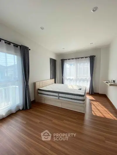 Spacious bedroom with large windows and wooden flooring, perfect for natural light lovers.