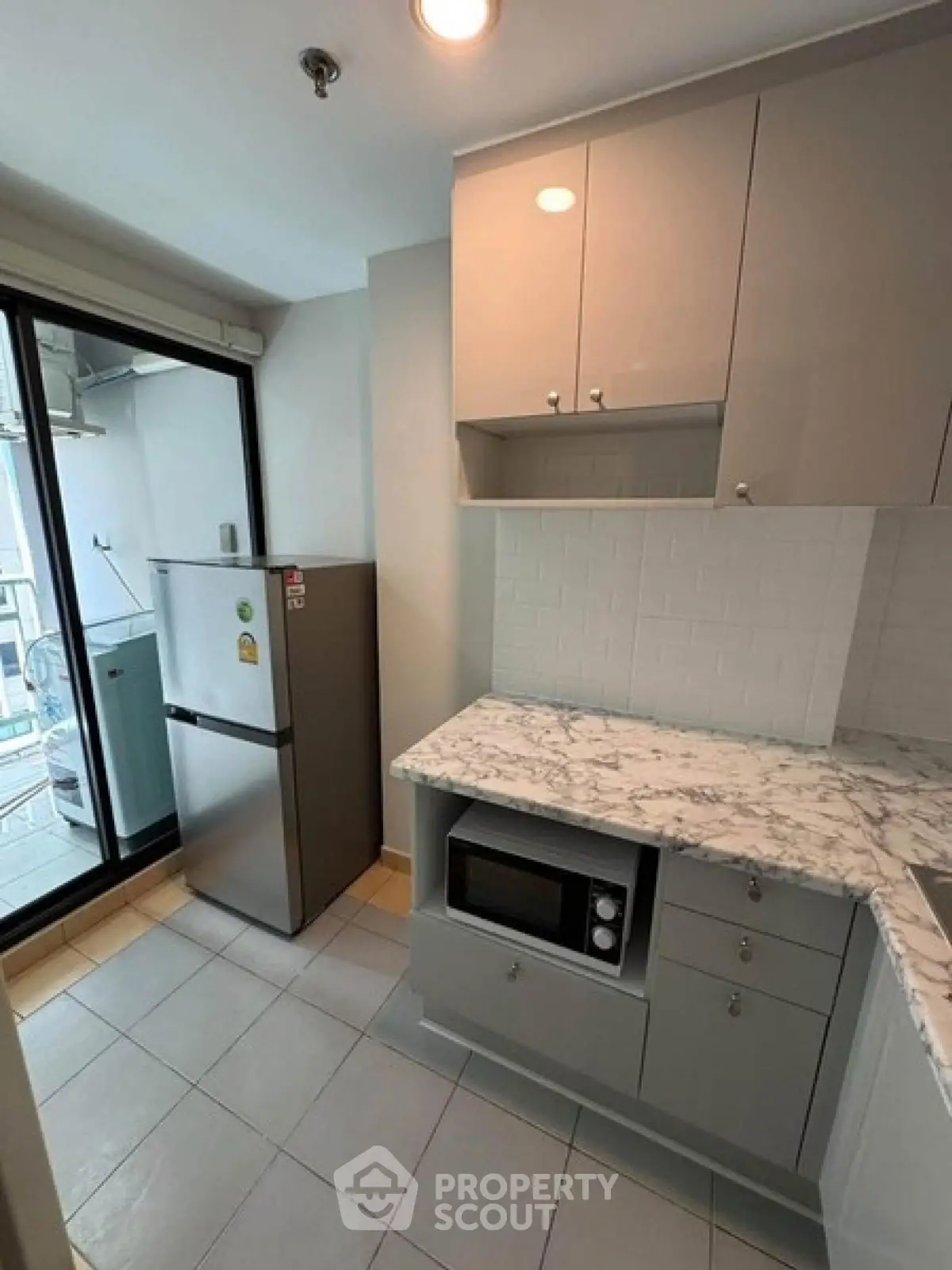 Modern kitchen with marble countertop and stainless steel appliances in a compact layout.