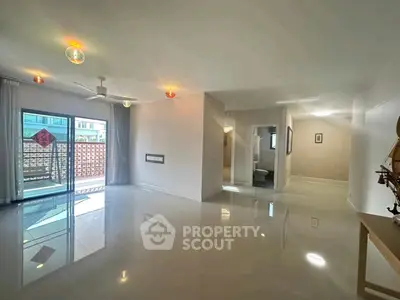 Spacious modern living room with glossy floors and balcony access in a contemporary apartment.