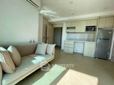 Modern living room with natural light, sleek furniture, and integrated kitchen appliances.