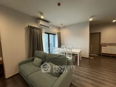 Spacious living room with modern furniture and dining area in open layout apartment.