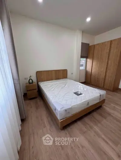 Spacious bedroom with wooden flooring and large wardrobe, perfect for modern living.