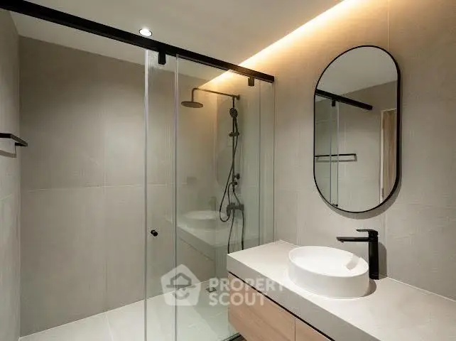 Modern bathroom with sleek shower and stylish vanity in contemporary apartment.