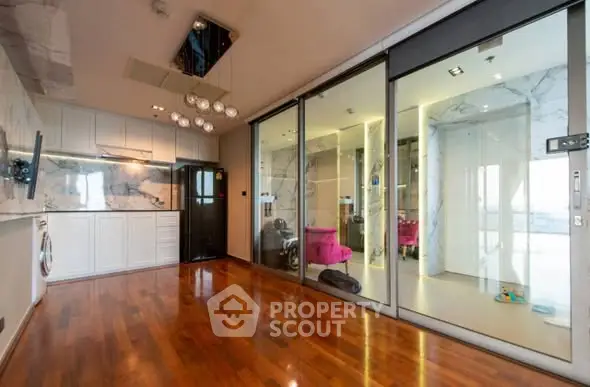 Luxurious modern living room with hardwood floors and glass partition, featuring elegant lighting and marble accents.