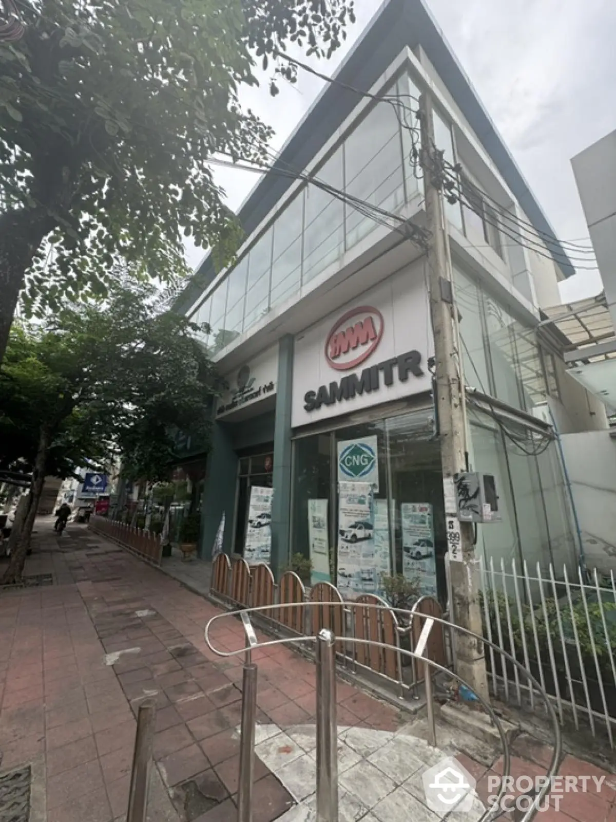 Modern commercial building with glass facade on a bustling street corner.