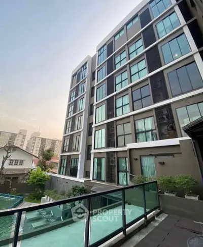 Modern apartment building with glass balconies and pool view