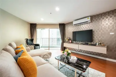 Modern living room with stylish decor, featuring a wall-mounted TV and elegant furniture.