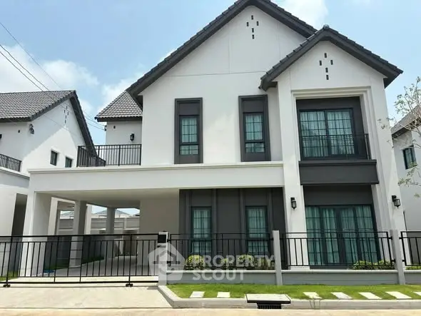 Modern two-story house with sleek design and gated entrance in suburban neighborhood.