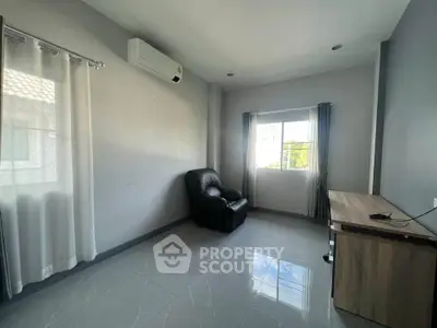 Spacious room with modern decor, featuring a comfortable armchair and large window for natural light.