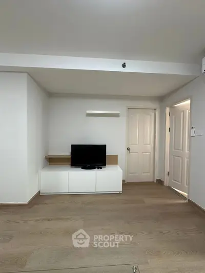 Modern minimalist living room with sleek TV stand and wooden flooring.