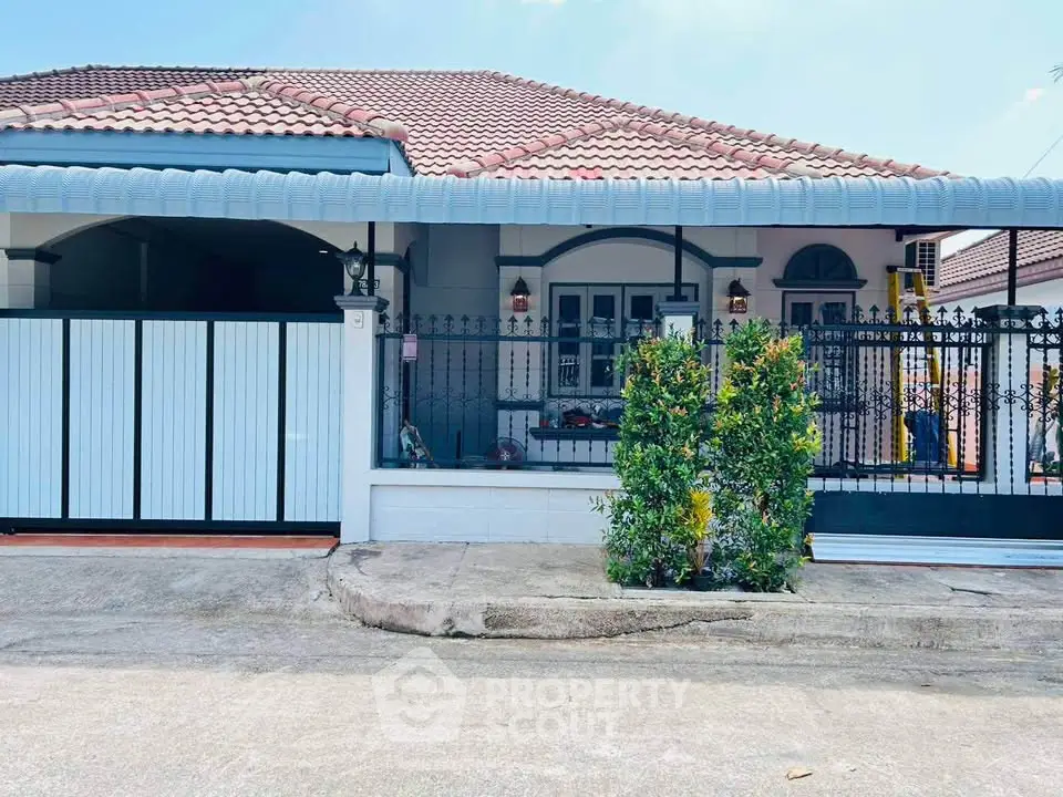 Charming single-story house with tiled roof and gated entrance in a serene neighborhood.