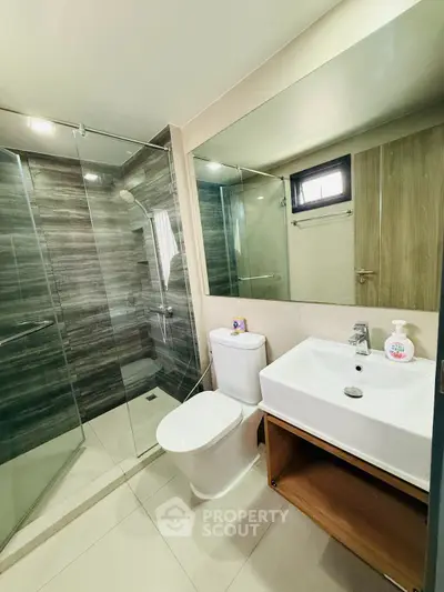 Modern bathroom with glass shower and sleek fixtures in contemporary apartment.